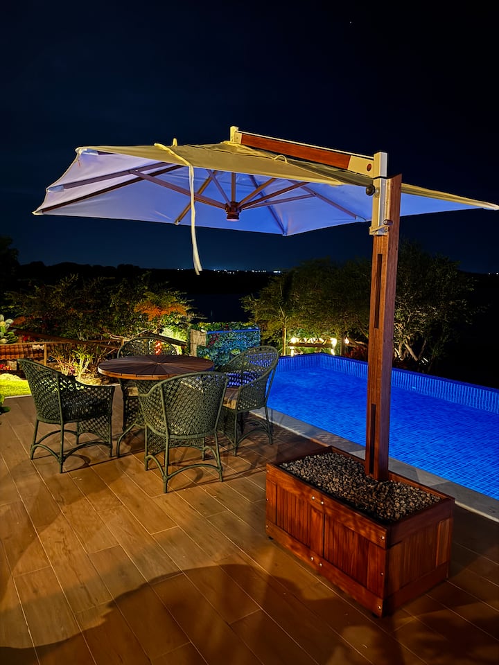 Mesa sob ombrelone ao lado da piscina à noite