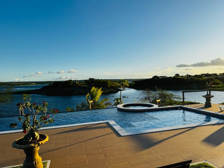 Piscina de borda infinita com jacuzzi, de frente para o rio