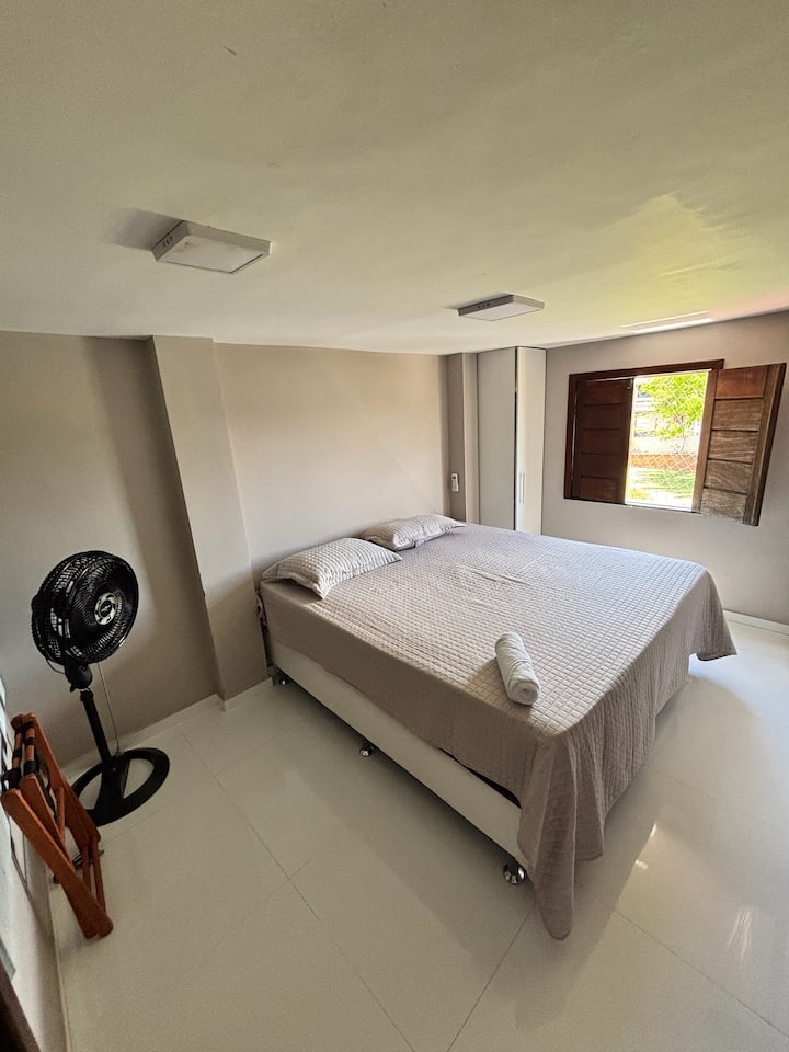 Quarto com cama de casal e janela de madeira