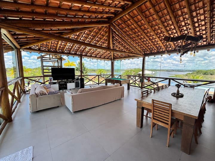 Varanda ampla com sofás, mesa de sinuca e vista para o rio